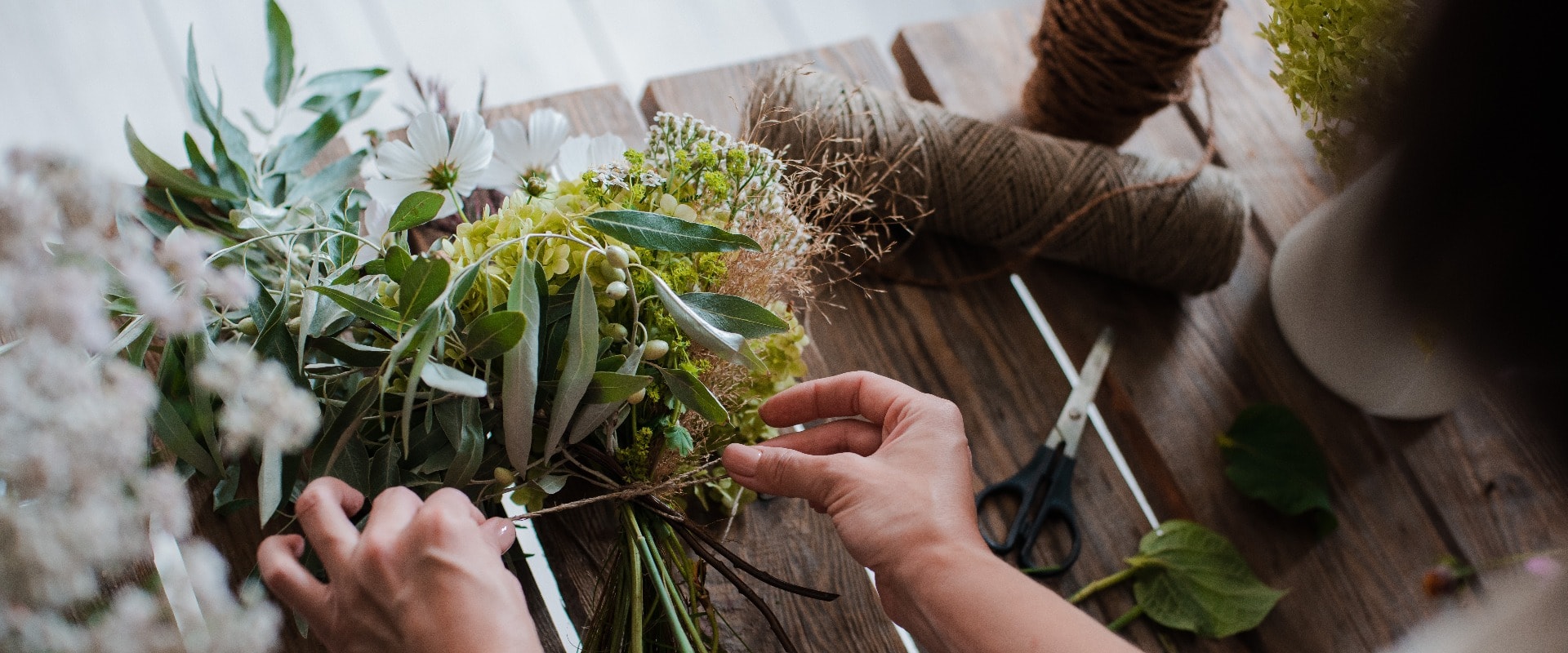 Female professional florist prepares the arrangement of wild flowers.