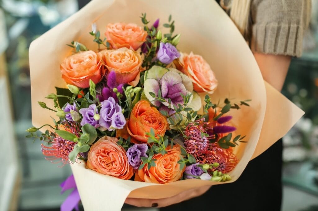 Female florist holding beautiful bouquet in flower shop