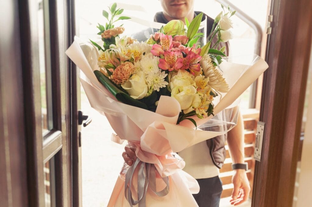 The delivery man delivers a bouquet of beautiful flowers to home
