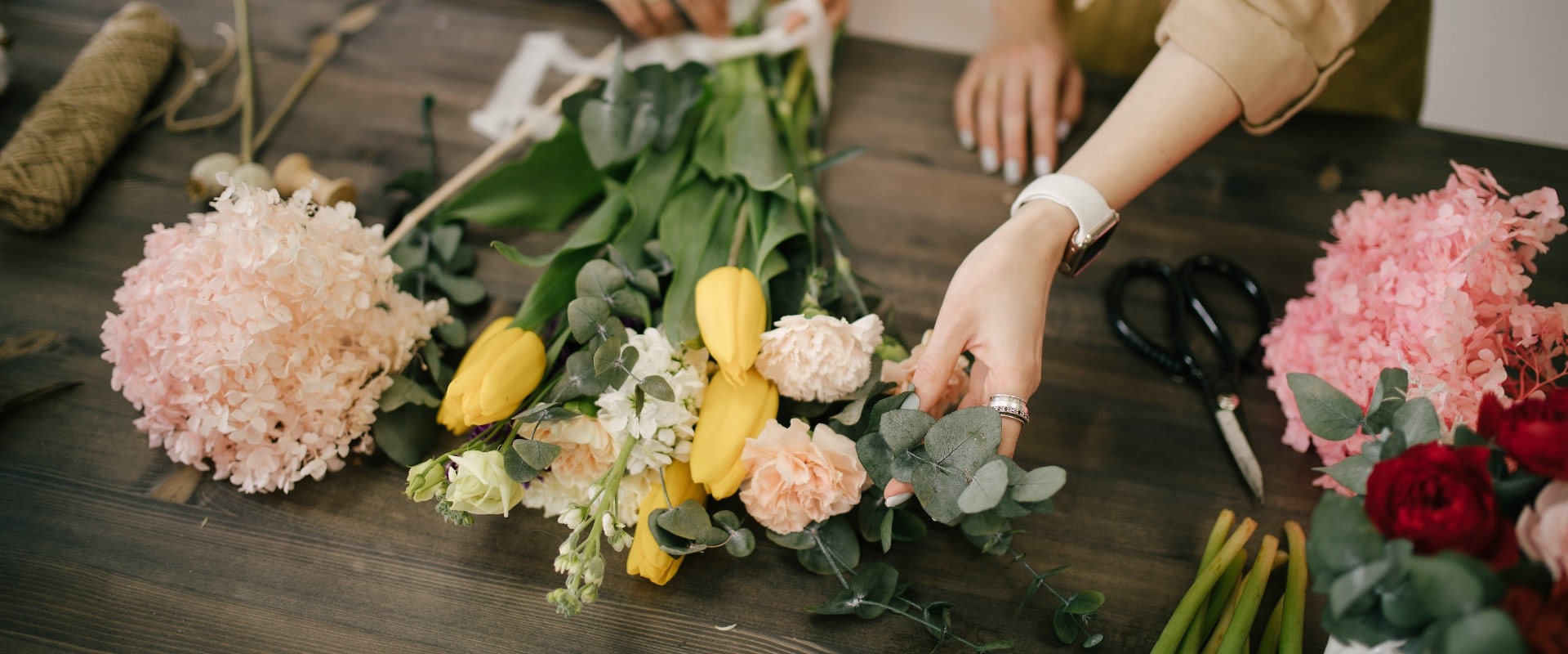 Two young women florist working in flower studio, making beautiful bouquet using fresh plants and flowers.